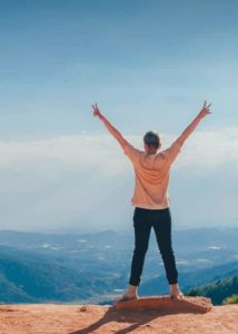 Person on top of the world with arms raised in wining pose